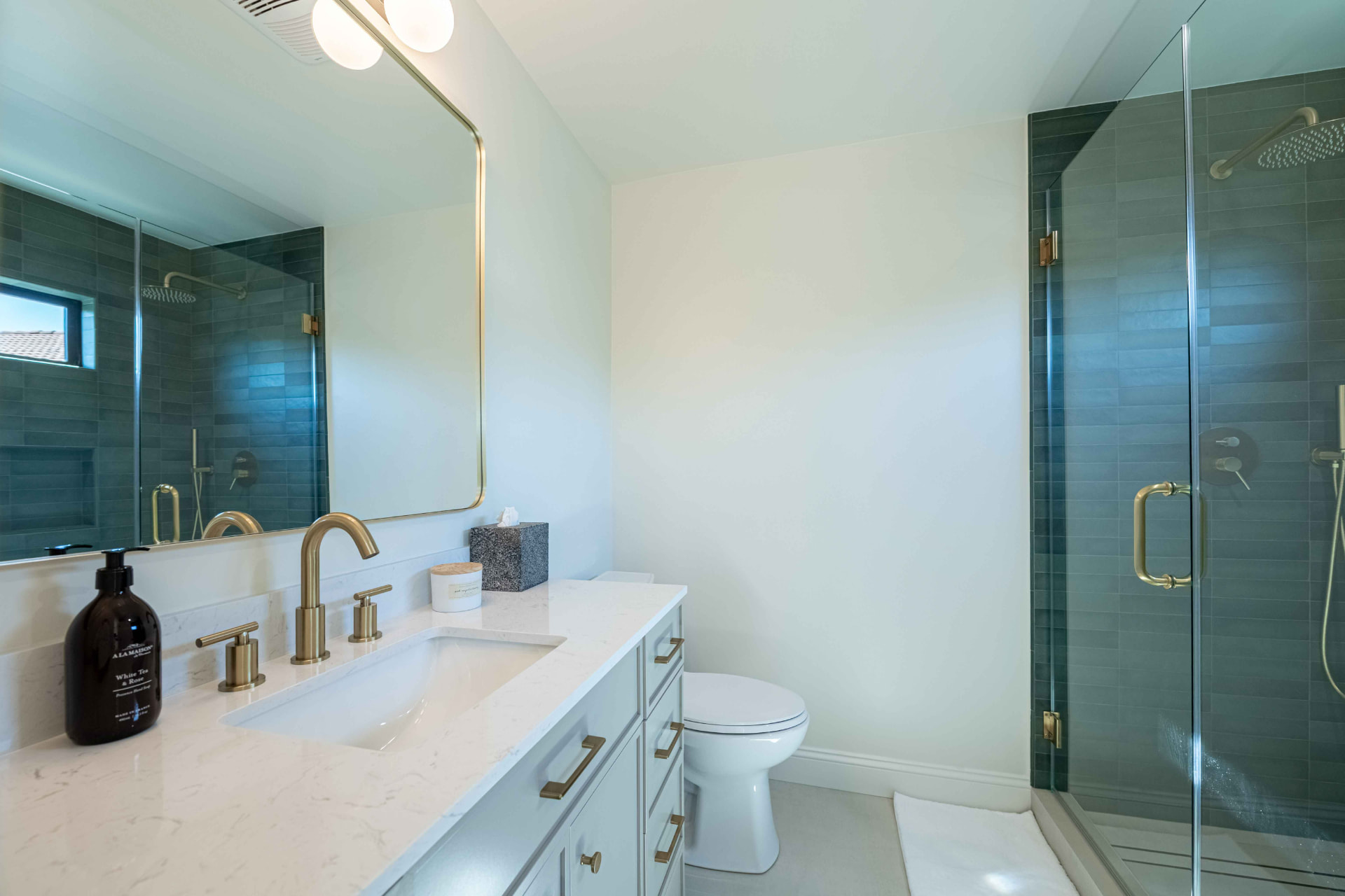 Guest bath with emerald tile and brushed brass fixtures